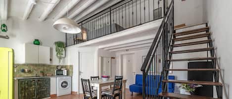 A modern apartment with a kitchen, dining area, and a staircase.