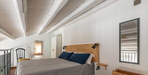 Un dormitorio con una cama, una mesita de noche, un cabecero de madera, un espejo y una pequeña mesa.