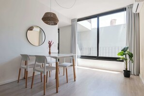 A modern dining area with a white table and chairs, a round mirror, and a hanging light fixture.