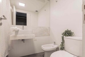 A bathroom with a sink, bidet, and toilet.