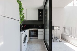 Una cocina compacta con lavadora, horno y una pequeña encimera.