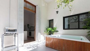 Une salle de bain moderne avec une baignoire en bois, une douche à parois de verre et un chariot muni d’un radiateur.