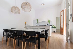 Una cocina moderna con gabinetes blancos, una isla central y lámparas colgantes de mimbre.