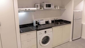 Une cuisine compacte équipée d’un lave-linge, d’un four à micro-ondes, d’un grille-pain et d’un réfrigérateur.