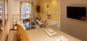 Un salon moderne avec un canapé, une table à manger et un téléviseur fixé au mur.
