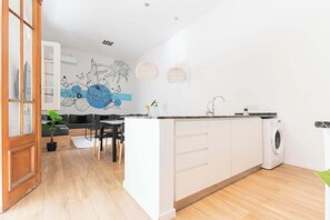 A modern kitchen with a central island, built-in appliances, and a dining area with a sofa and chairs.