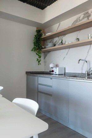 Une cuisine moderne avec un dosseret en marbre, des étagères en bois et un plan de travail blanc.