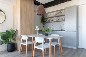 Une cuisine moderne avec des armoires blanches, un pare-feu en marbre et un luminaire suspendu.