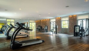 Un gimnasio amplio con cintas de correr, máquinas de pesas y un espejo grande.