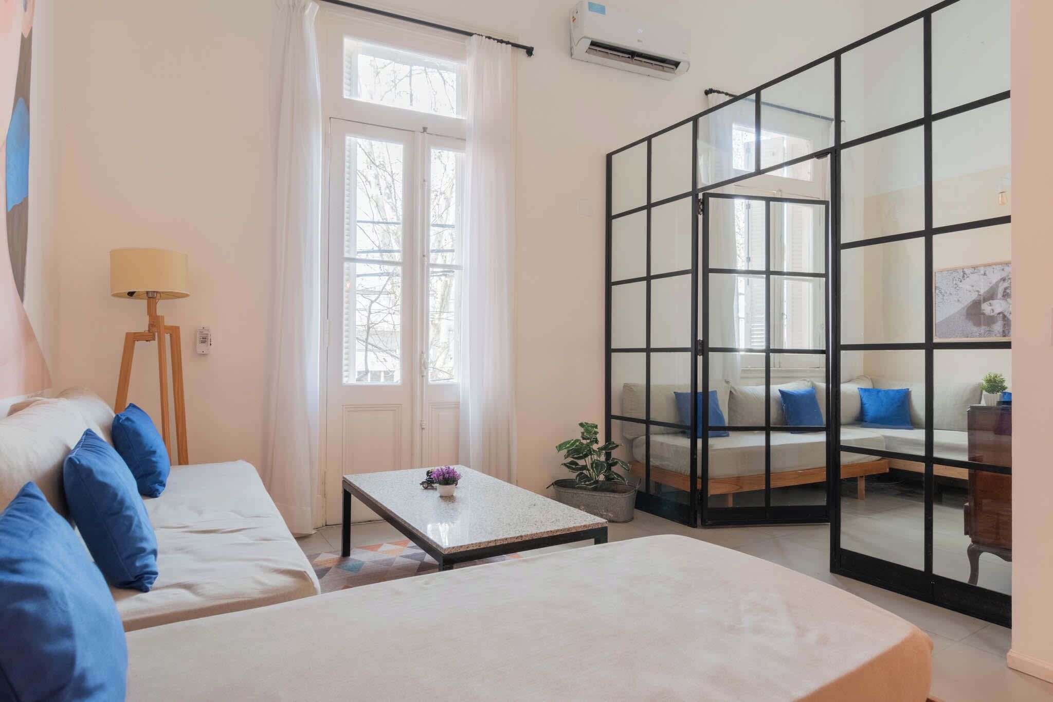 Una habitación con una cama, un sofá, una mesa y un ventanal corredero que da a un balcón.