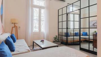 Una habitación con una cama, un sofá, una mesa y un ventanal corredero que da a un balcón.