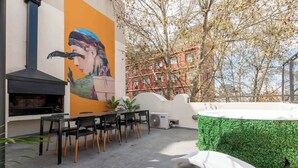 A rooftop patio with a grill, seating, and a mural.
