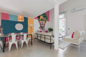 Una sala de estar moderna con comedor, un sofá, una cama y un mural grande en la pared.