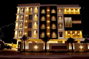 Un hotel moderno con varios pisos, ventanas iluminadas y una entrada bien iluminada.