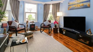 A living room with a large TV, comfortable seating, a fireplace, and a view of the outdoors. - English Riviera Coastal Holiday Home in Devon Uk (Paignton)