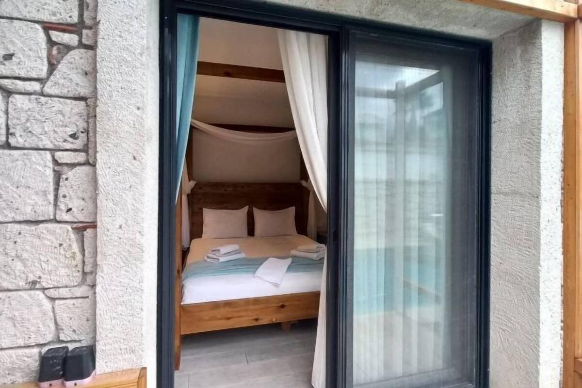 A bedroom with a wooden bed, white linens, and a sliding glass door leading to a balcony.