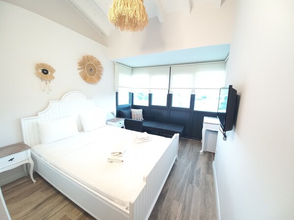 A bedroom with a bed, bedside table, nightstand, and a window with a view.