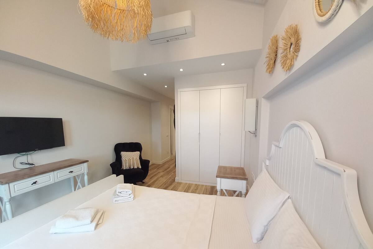 A bedroom with a bed, a desk, a chair, a television, and a wardrobe.