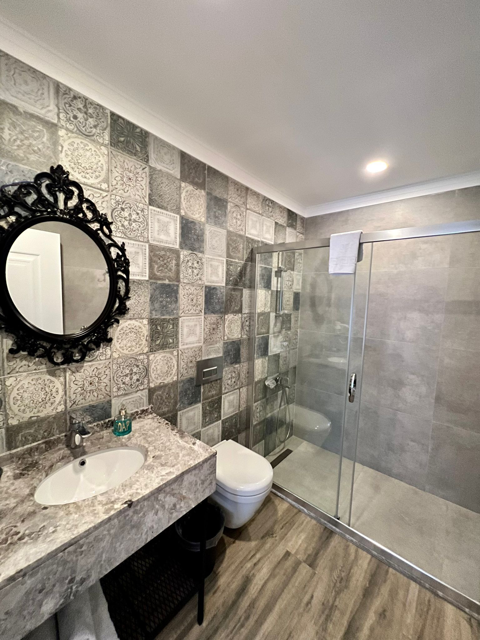 Une salle de bain avec un lavabo en marbre, des toilettes et une douche à parois de verre.