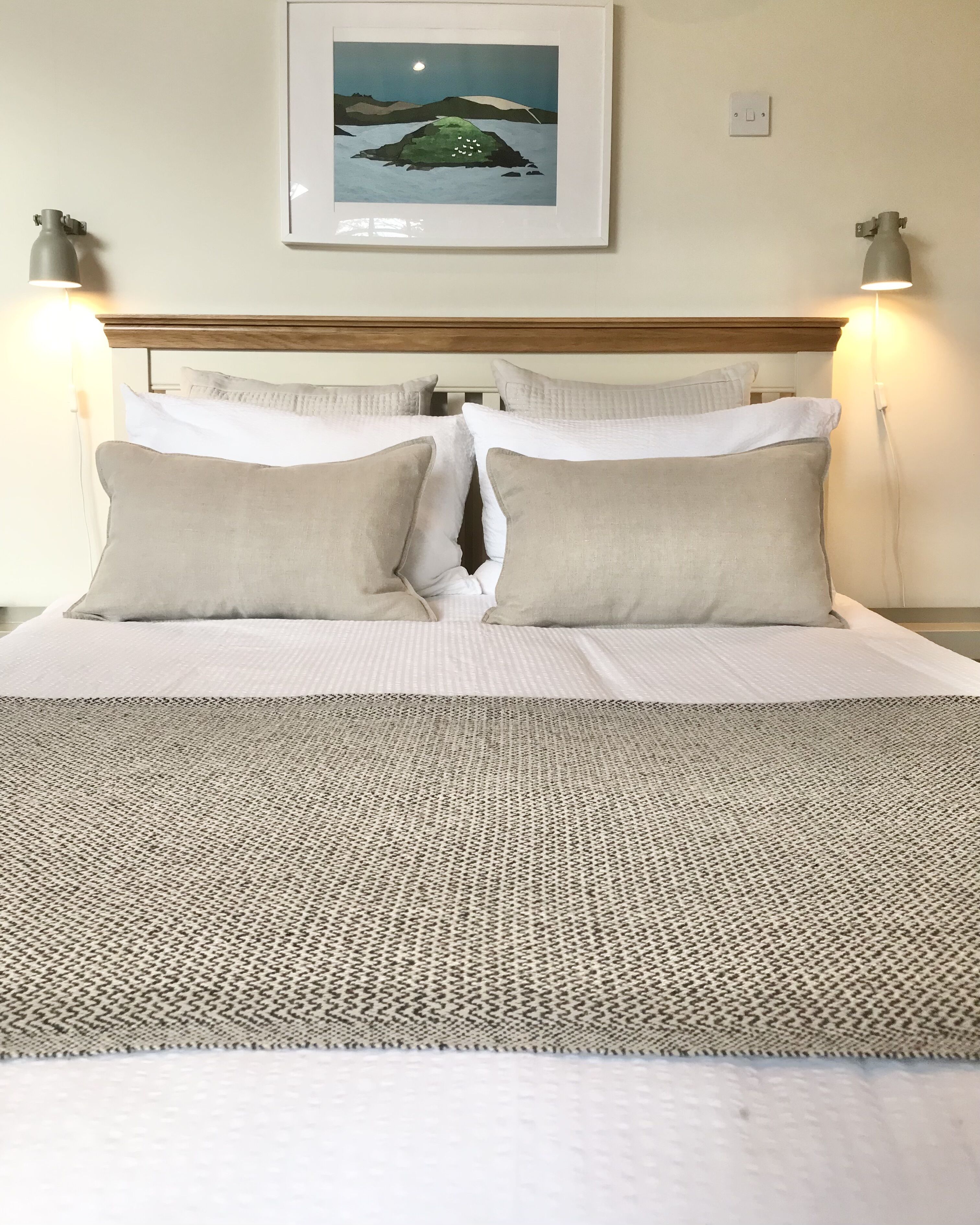 A neatly made bed with a patterned bedspread, two pillows, and a framed picture above it.