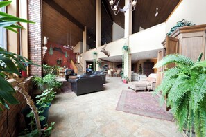 A spacious lobby with a fireplace, leather seating, and a variety of plants.