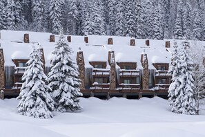 A snow-covered lodge with multiple balconies and a stone facade.