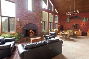 A cozy lounge area with a fireplace, leather sofas, and a dining area with a wooden table and chairs.
