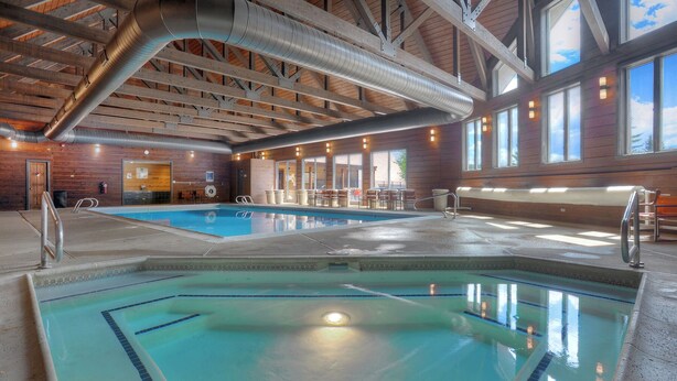 An indoor swimming pool with clear lanes, a lounge area with seating, and large windows allowing natural light. - Silver Vista End Unit | Pool & Ski Shuttle, Hot Tub, Fireplace, Balcony (Durango)