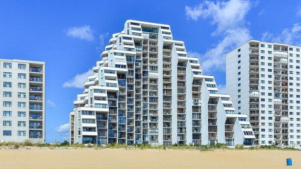 Un hotel moderno de altura con varios balcones y vista al mar.