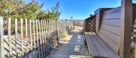 A wooden bench and a pathway leading to a beach.