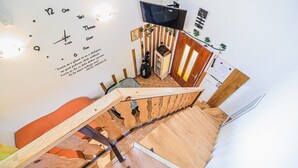 Moderni sisustus, jossa on puinen portaikko, seinälle asennettu televisio ja seinäkello.