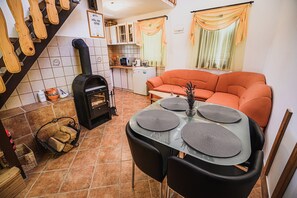 Een gezellige zithoek met een open haard, een oranje bank en een eettafel met placemats.