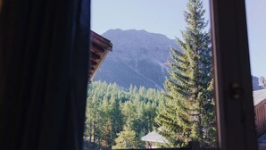 A mountain view through a window with a wooden structure in the foreground.