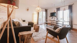 A modern living room with a sofa, armchairs, a coffee table, and a dining area with a table and chairs.