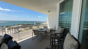 Un balcon avec vue sur l’océan, une table avec des chaises et un canapé.