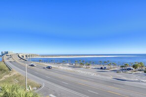 Una carretera costera con vista a la playa, palmeras y un puente.