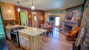 A kitchen with a central island, wooden cabinets, and a stone fireplace. - Cozy Stone Cottage overlooking Smith Lake (Marcell)