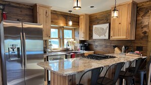 A modern kitchen with wooden cabinetry, stainless steel appliances, and a granite countertop. - Cozy Stone Cottage overlooking Smith Lake (Marcell)