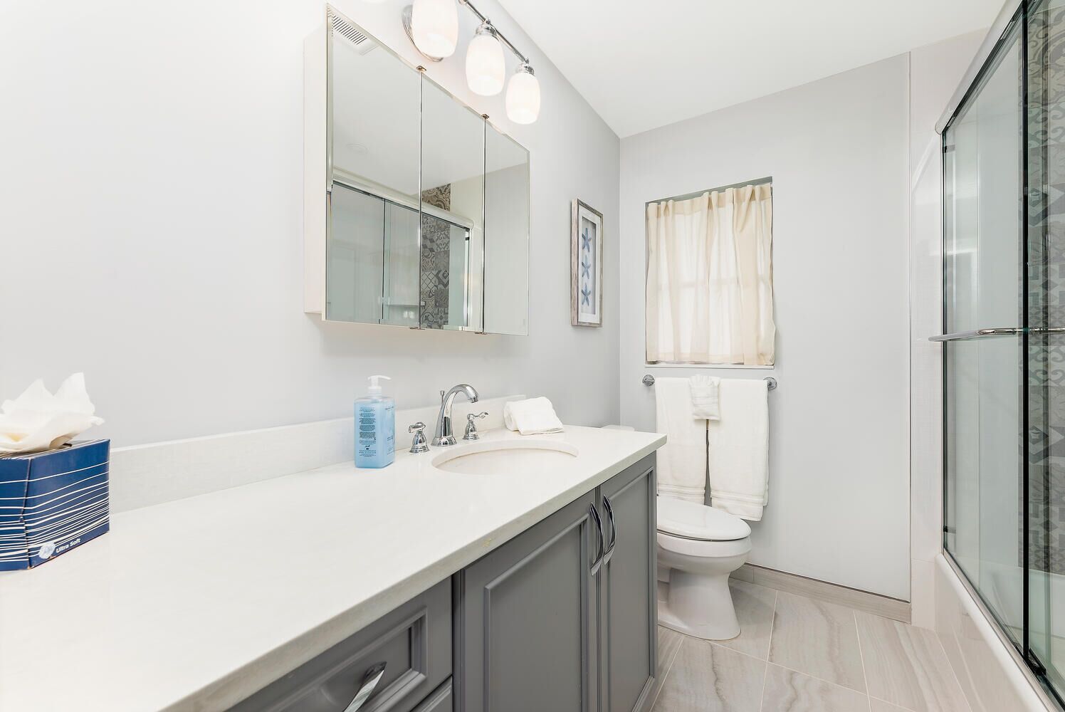 Un baño moderno con un lavamanos, espejo y váter blancos.