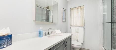 Un baño moderno con un lavamanos, espejo y váter blancos.