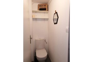 Bathroom with a toilet and wall-mounted shelf featuring a WiFi password sign.