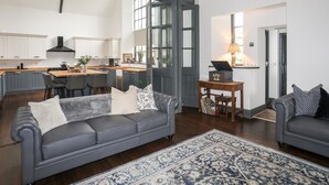 Un vaste espace de vie comprenant un canapé gris, une table basse et un tapis bleu à motifs.
