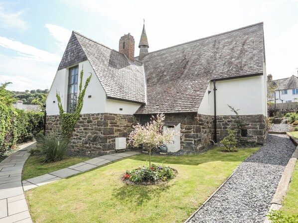 A traditional stone and white house with a sloped roof and a small tower.