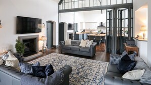 Un salon spacieux avec une cheminée, un grand canapé et un tapis à motifs.