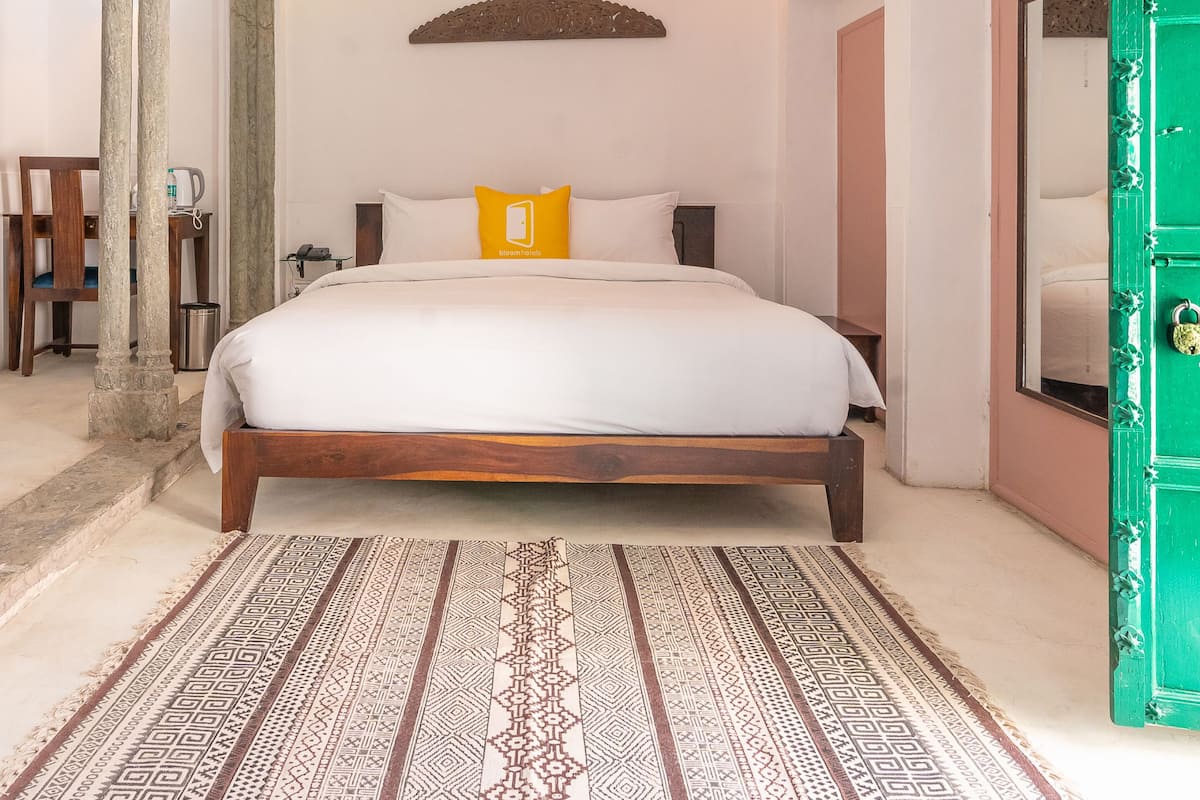 Quarto bem arrumado com cama, ventoinha no teto e tapete estampado.