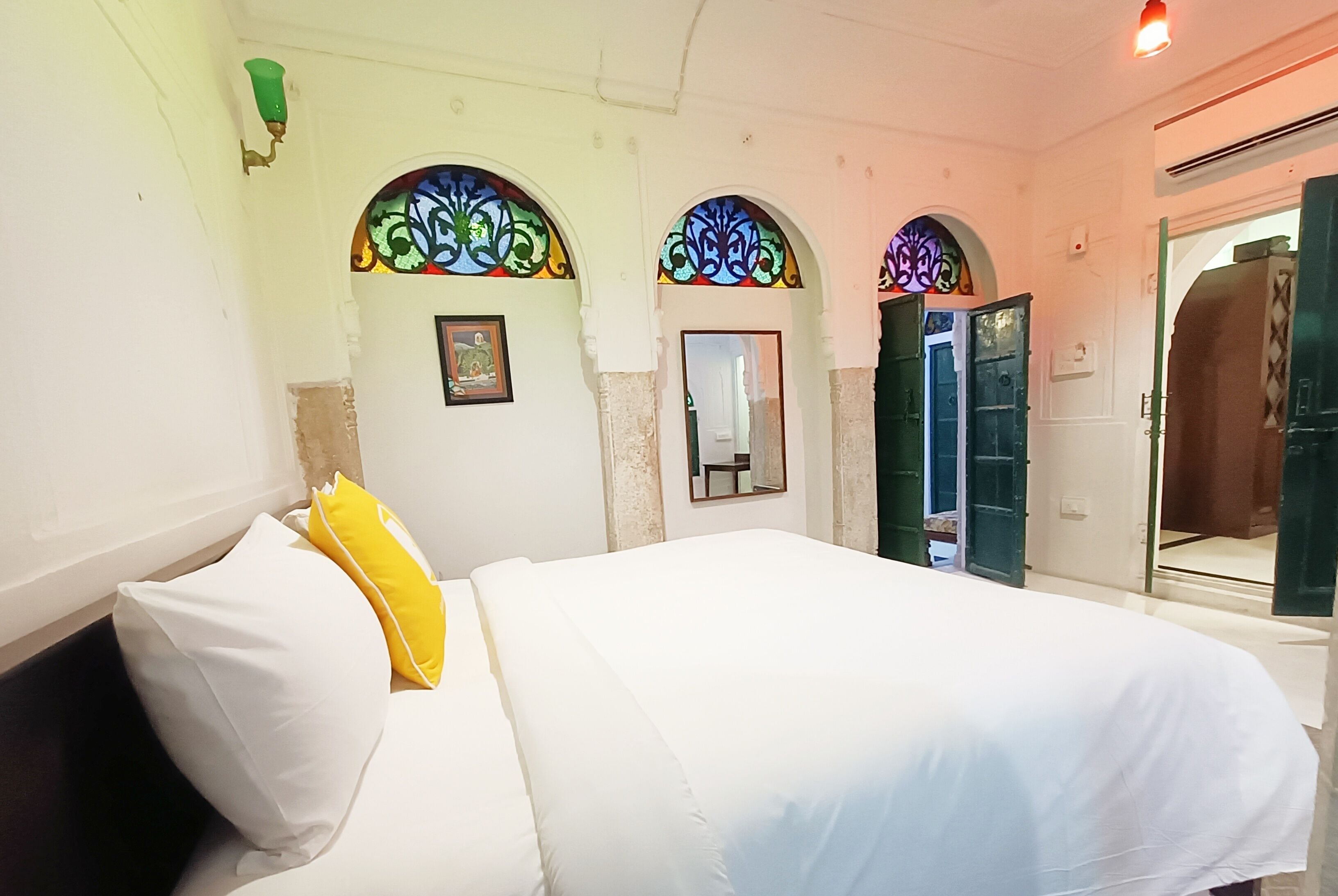 A bedroom with a bed, a mirror, and a door.