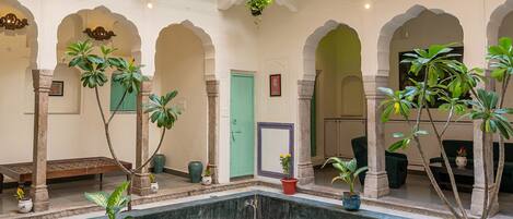 A spacious courtyard with a central fountain, surrounded by potted plants and a seating area.