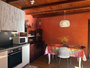 A kitchen with a microwave, oven, wooden cabinets, and a dining table with chairs. - Ground floor with garden and barbecue - Puig Falcó 2 (Pla de l'Ermita)