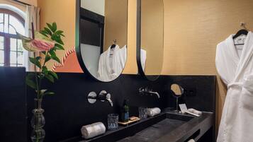 A modern bathroom with a black sink, a mirror, and a towel rack.