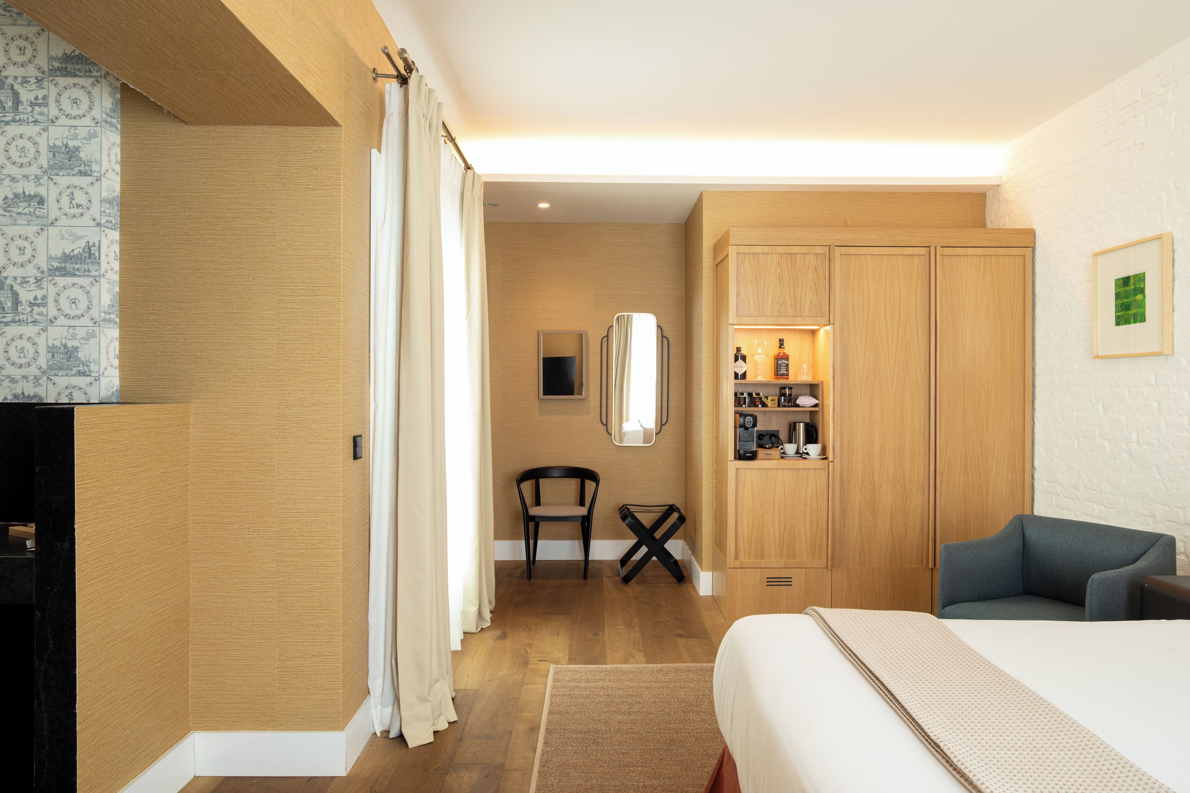 A hotel room with a bed, a desk, a chair, and a wardrobe.